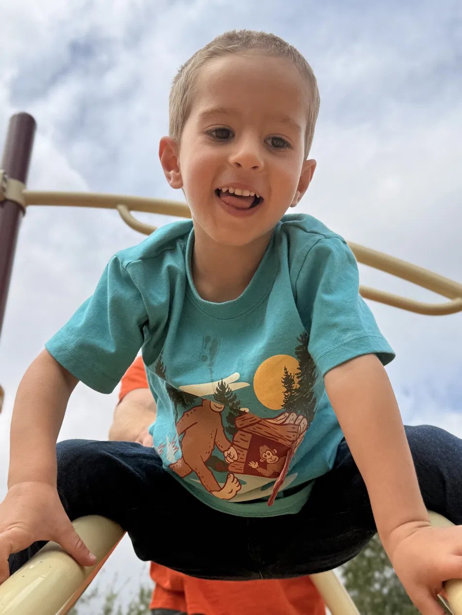 A laughing preschooler climbing on the play structure